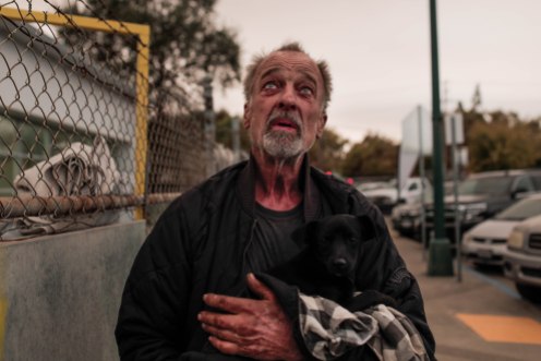 Daniel Woida holds a dog he rescued outside of a shelter at the Butte County Fairgrounds in Gridley, Calif., on Friday, Nov. 9, 2018. Many evacuees of the deadly Camp Fire came to the shelter. (Randy Vazquez/Bay Area News Group)